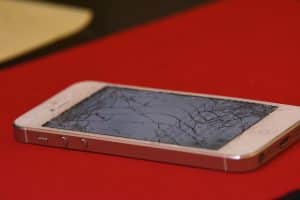 Un iphone blanc sur fond rouge avec écran cassé