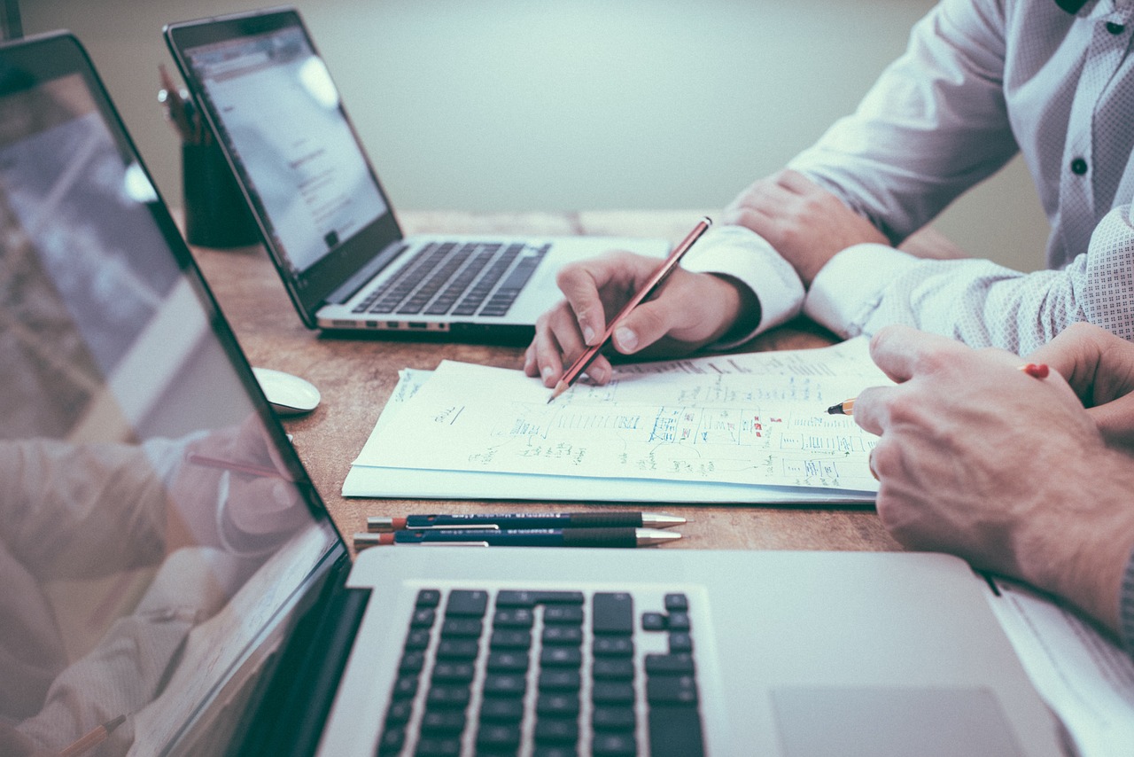 deux personnes travaillant sur ordinateur portable papier stylo